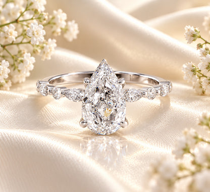 Dewdrop Pear Engagement Ring in 925 sterling silver with pear-shaped cubic zirconia center and marquise and round accents on white satin with baby's breath